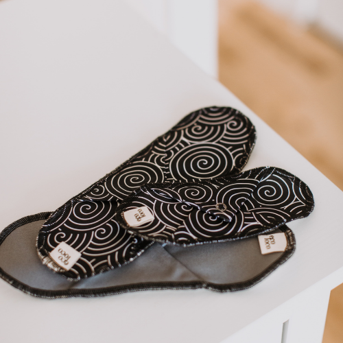 Serviette hygiénique lavable avec des motifs de spirales noires et blanches, protège-dessous lavable.