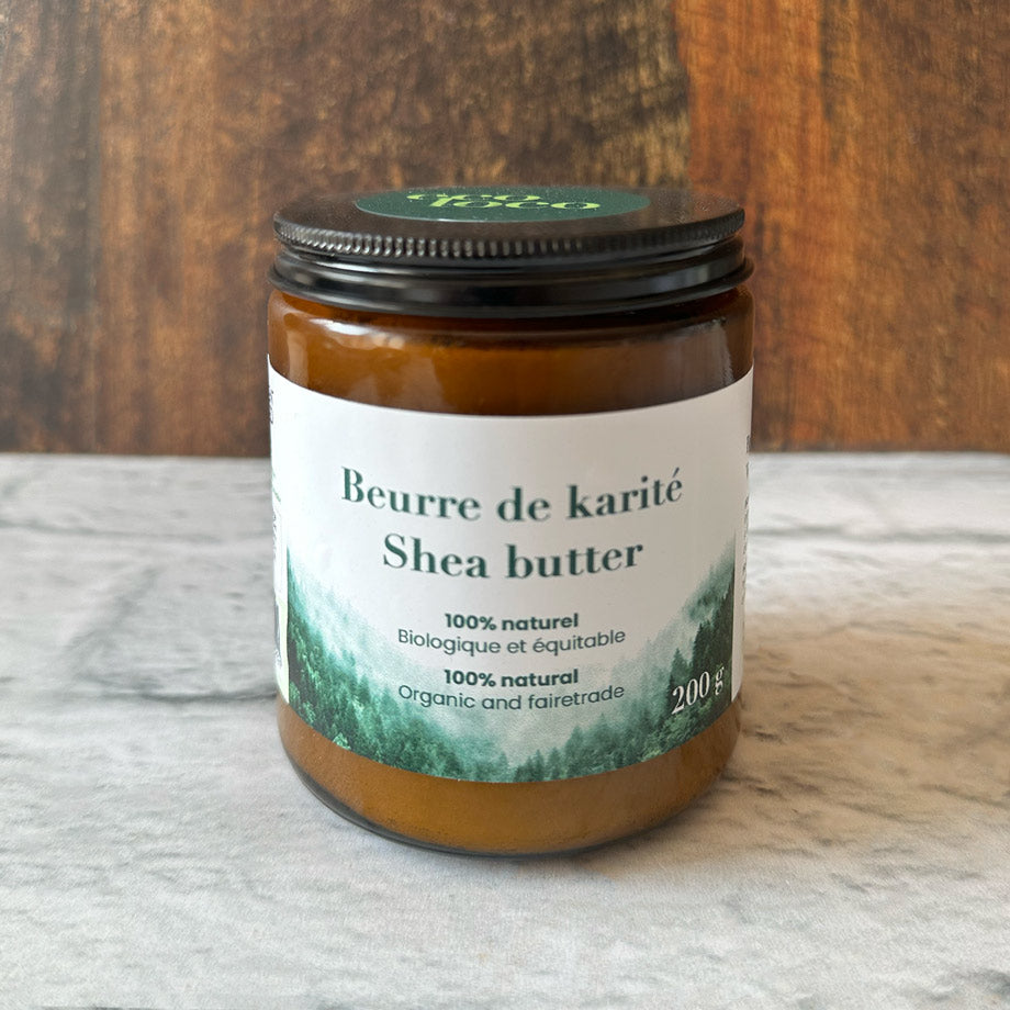 Pot de beurre de karité dans une main sur fond de bois