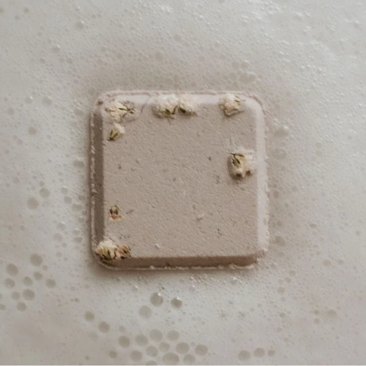 Un petit carré blanc parsemer de petites fleures blanche entourer de mousse de bain.