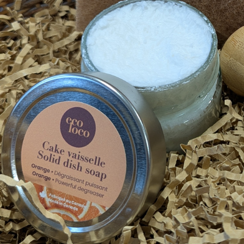 Petit cake vaisselle à l'orange ouvert dans un panier en osier avec un tampon à récurer recyclé.