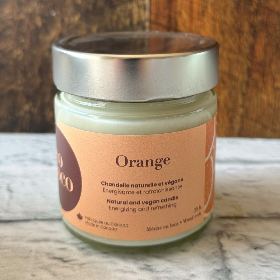 Chandelle naturelle et végane 35 heures sur un comptoir blanc avec un fond de bois fabriquée par Eco Loco de senteur Orange
