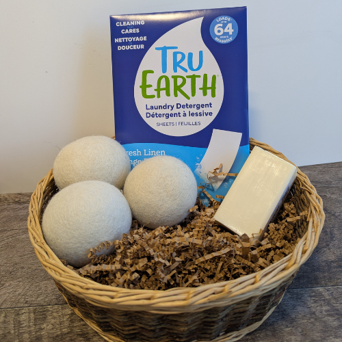 Ensemble de lessive écologique dans un panier comprenant des balles de séchage, une barre détachante et un paquet d'éco-feuille de lessive.