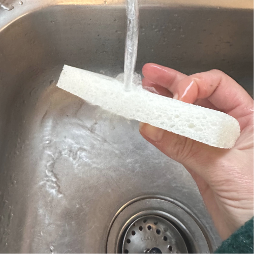 éponge en cellulose biodégradable blanc en dessous de l'eau du robinet