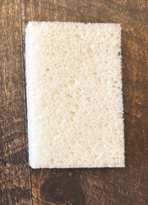 Éponge rectangulaire blanche sur un fond en bois foncé