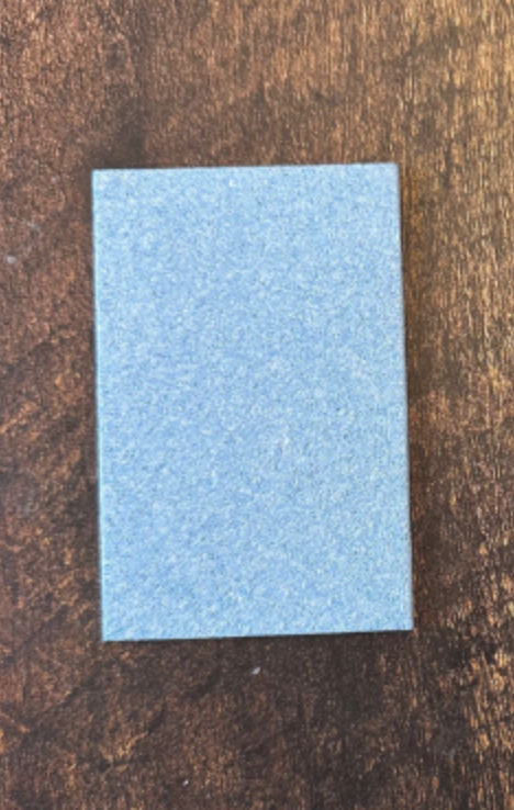 Éponge rectangulaire bleue sur un fond en bois foncé