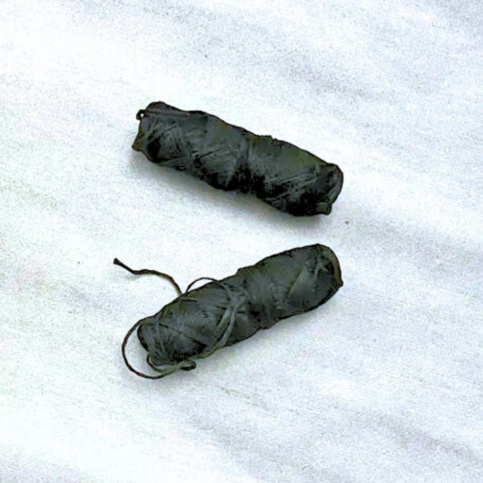 Deux bobines de fil soie dentaire noire compostable et végan sur un fond blanc marbre