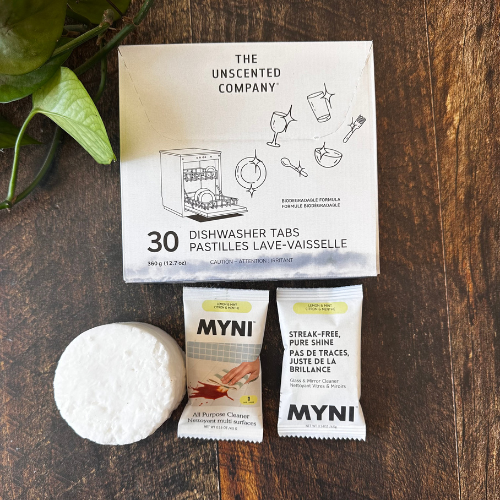 Ensemble de savon solide pour l'entretien ménager composé d'un cake vaisselle, de 2 pastilles Myni et d'une boite de savon à vaisselle unscented, présentés sur un planche en bois.