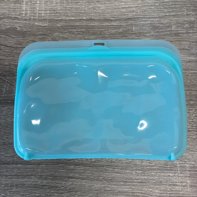 Un moyen sac en silicone bleu déposé sur une planche en bois.