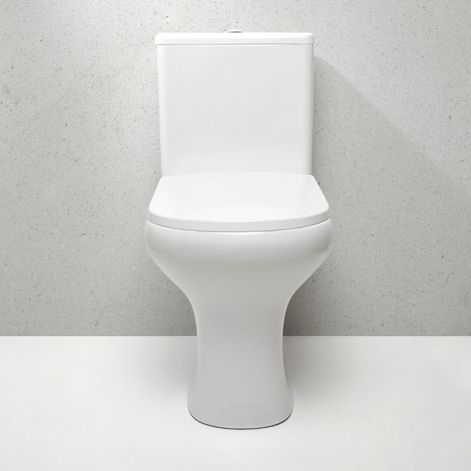 Toilette blanche bien propre qui se tient sur un mur de béton gris pâle et un plancher tout blanc