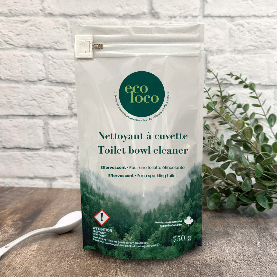 Pochette en Eco Loco de nettoyant à cuvette toilette sur un fond de mur de briques blanches avec des feuilles vertes et une cuillère blanche