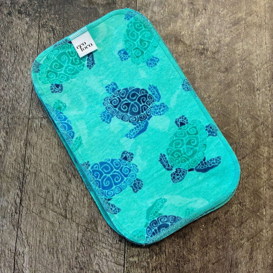 Papier de toilette turquoise avec motif de tortue et l'étiquette Eco Loco sur une planche de bois