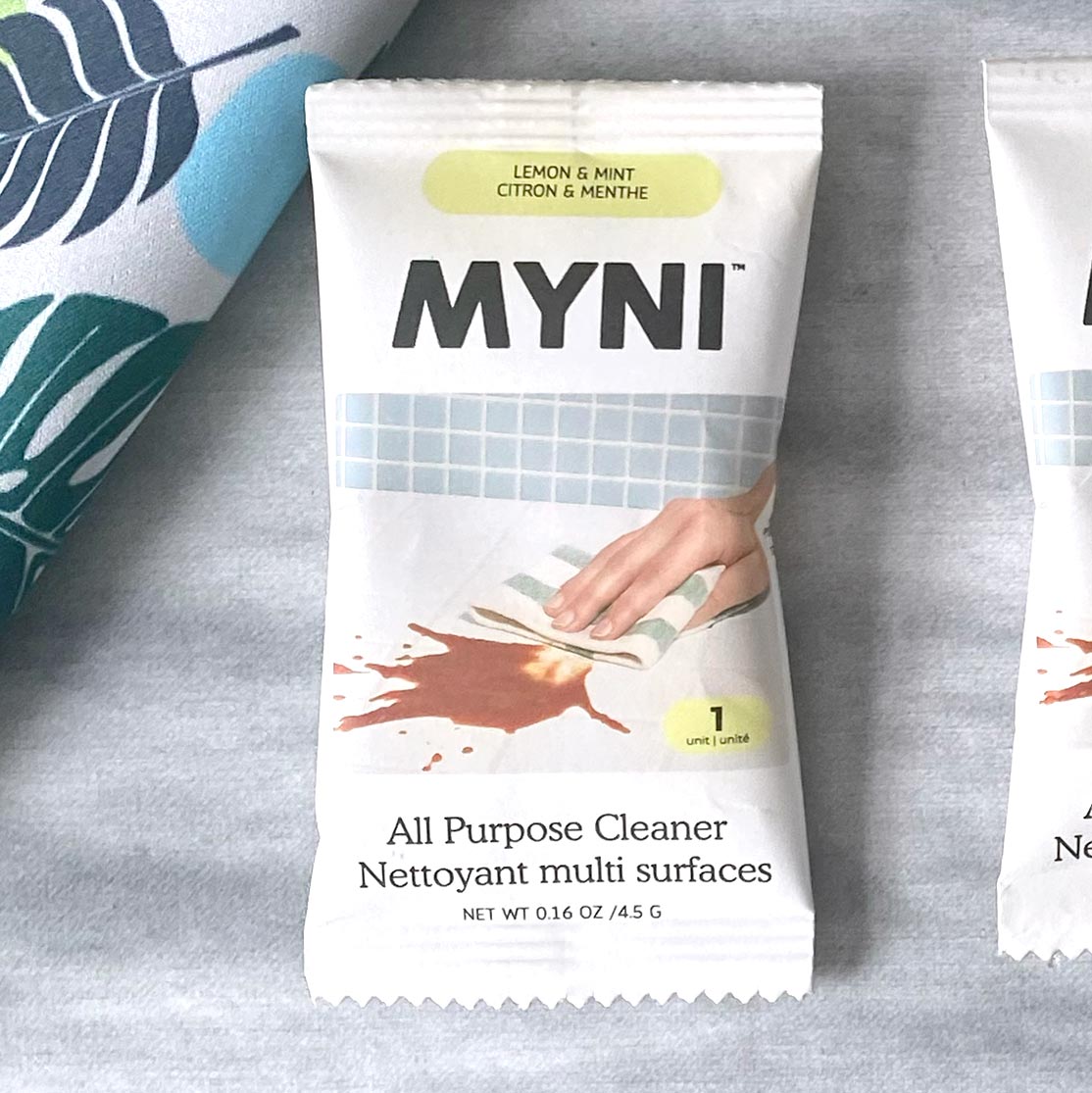 Petit sachet blanc écrit Myni Citron & menthe nettoyant multi surfaces sur un fond de textile gris