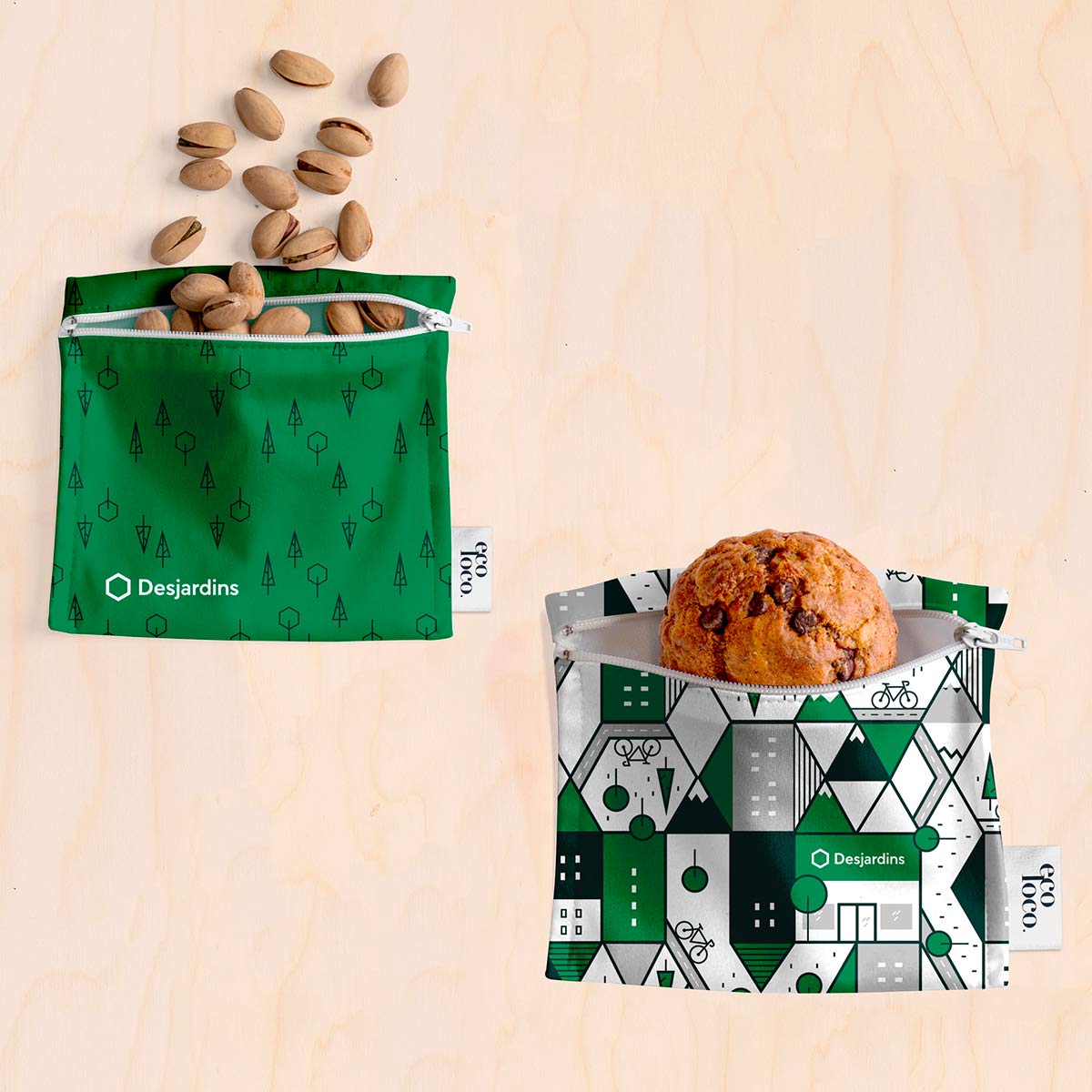 Deux sacs mini petit vert avec les logo de Desjardins contenant un muffin et des noix pistache sur un fond texturé de bois