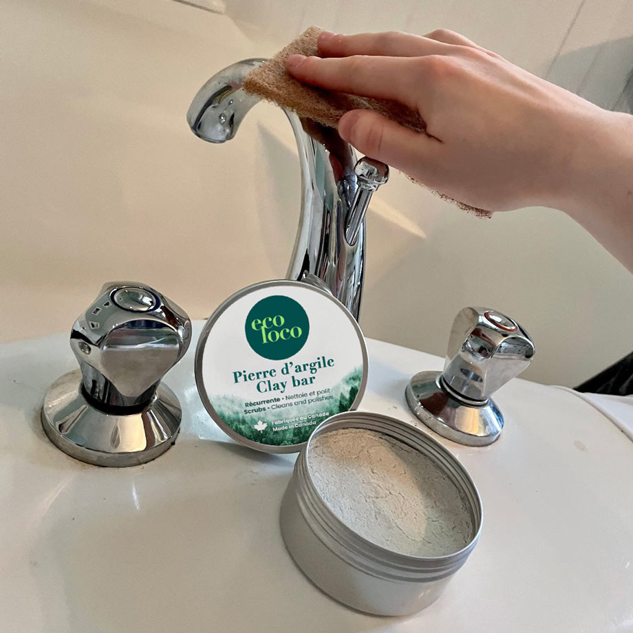 Main qui lave un dessus de roniet en argent dans une salle de bain avec une pierre d'argile fabriquée par Eco loco et une éponge en fibre de noix naturelle