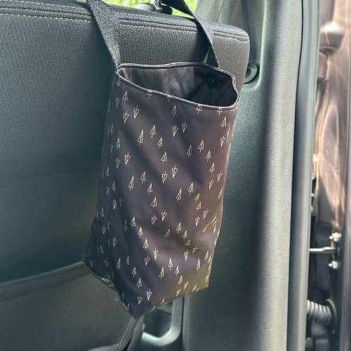 Poubelle de voirure noire avec des motifs de sapin accrochée sur l'appui tête.