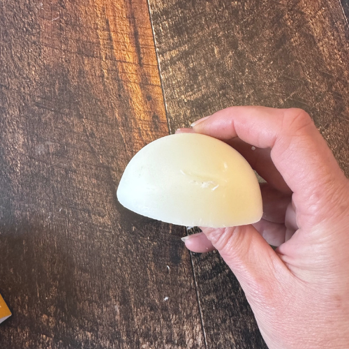 Revitalisant en barre tenu dans une main au dessus d'une planche de bois