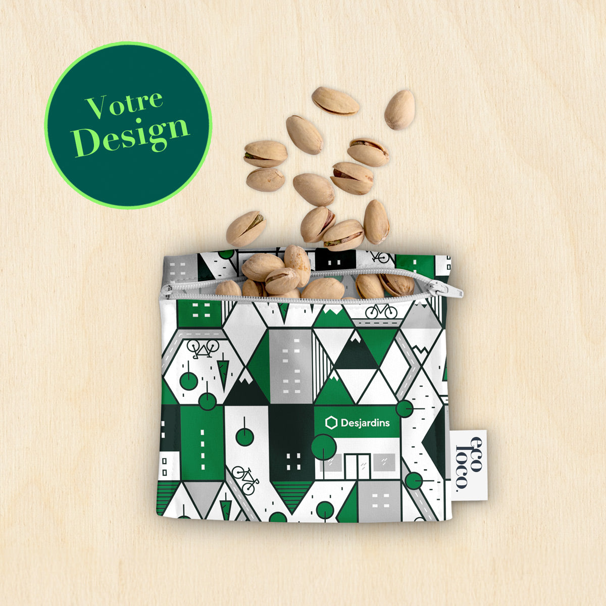Petit sac à collation réutilisable et lavable avec le logo Desjardins et la mention Votre Design contenant des pistaches sur un fond de bois