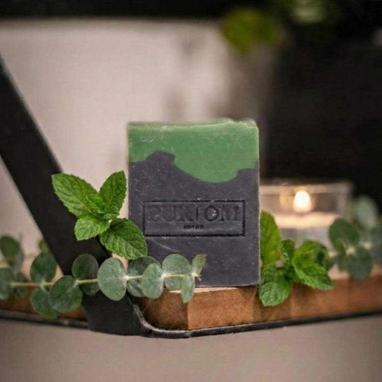 Savon avec des feuilles de menthe et d'eucalyptus sur un porte savon et un fond de chandelle à massage