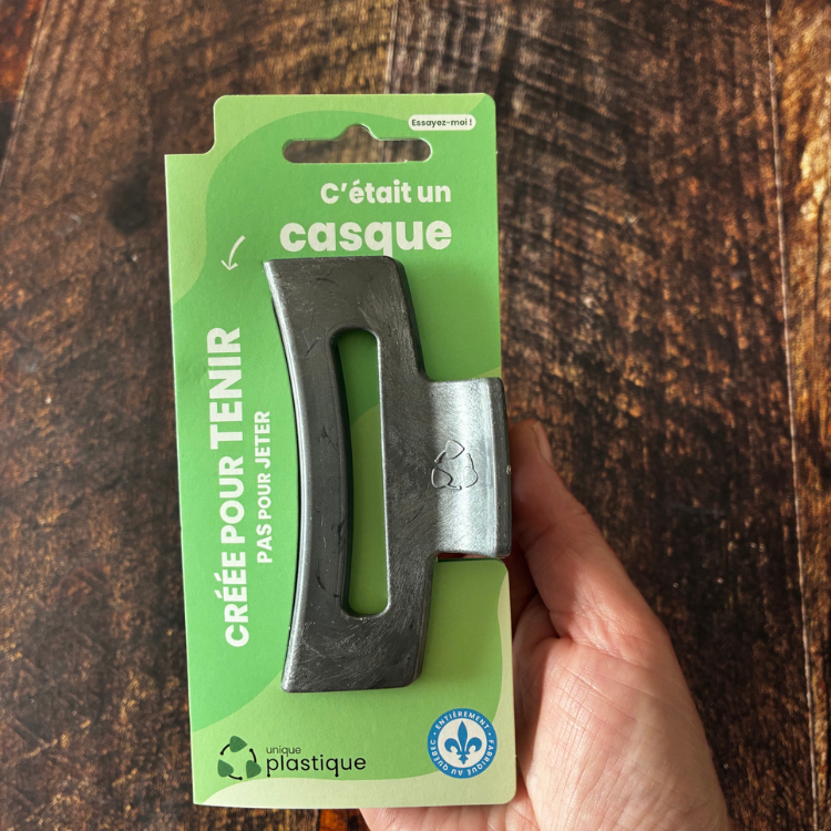 Moyenne pince à cheveux brune avec un logo de matériau recyclé et son emballage cartonné vert qui dit: C'était un casque, créée pour tenir pas pour jeter, Unique plastique et le logo fait au Québec.