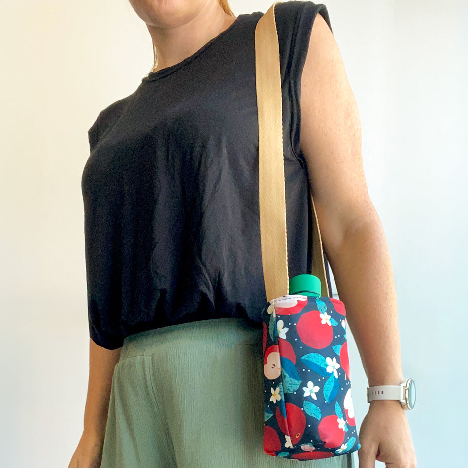 Femme qui tient sur son épaule un sac de transport pour bouteille d'eau réutilisable