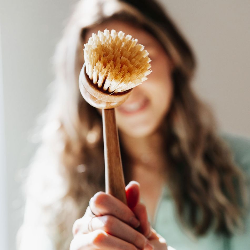 Jeune femme qui tient une brosse à long manche en bois