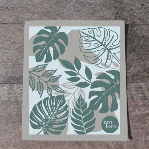Chiffon suédois qui remplace les essuie-tout avec un motif de feuilles tropicales sur une planche de bois.