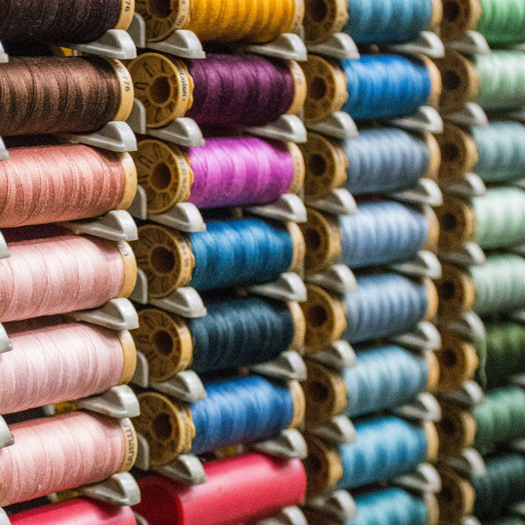 Bobines canettes de fils colorées rangés sur un présentoir en hauteur