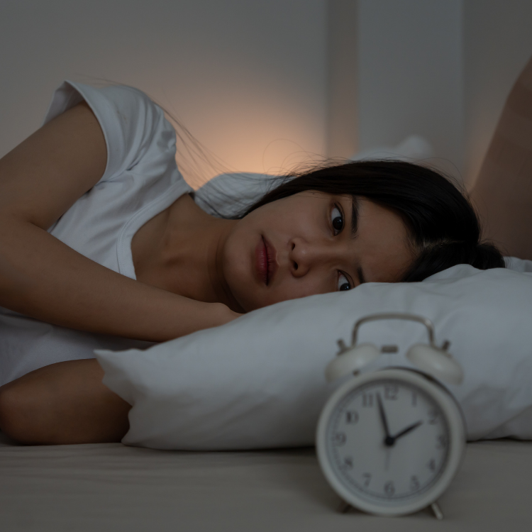 Une femme les yeux ouverts à deux heures du matin dans son lit démontrant qu'elle fait de l'insomnie.