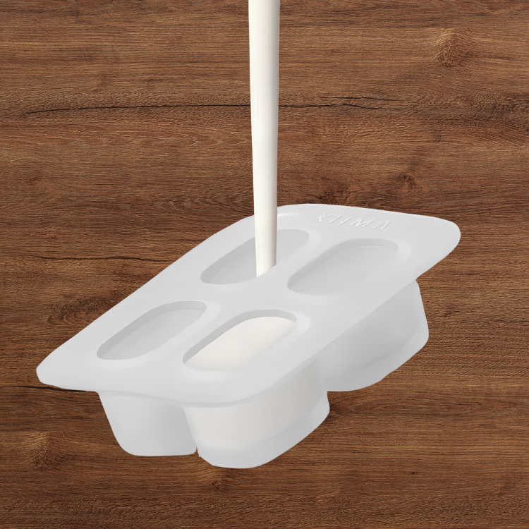Un moule en silicone pour recharge de baume à lèvres avec un liquide blanc qui coule dedans et un arrière-plan de bois.
