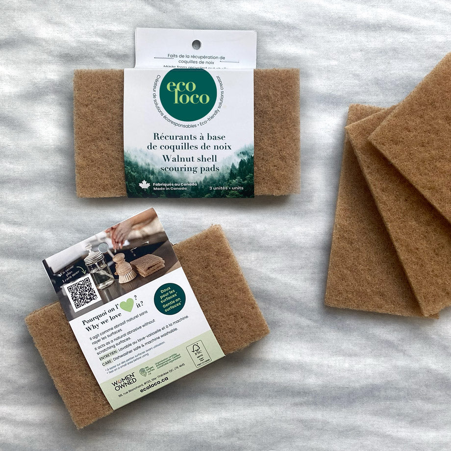 Tampons récurrents faits de coquilles de noix qui sont dans leur emballage Eco Loco de carton en ensemble de trois sur un fond blanc effet gris de marbre