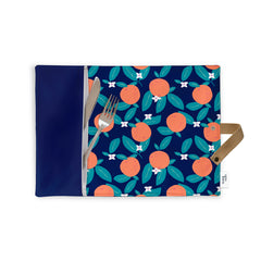 Napperon de tissu réutilisable avec des motifs d'oranges avec des petites fleurs blanches ainsi qu'une fourchette et un couteau à beurre qui sortent partiellement de la poche. Sur fond blanc avec une ganse beige