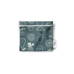 Un sac réutilisable en tissu pour les collations, sandwich, noix, biscuits, crudités, de couleur gris avec des dessins de citron, légumes, oranges, radis, muffins, cerises, petits pois, pommes. Le sac est à plat sur un fond blanc.