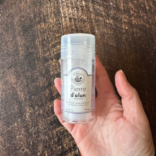 Pierre d'alun dans un contenant en plastique tenu par une main