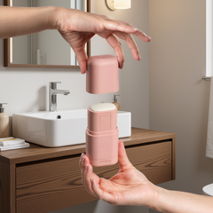 Des femmes de femmes qui tiennent un applicateur réutilisable rose de déodorant ouvert sur lequel il est écrit KIIMA et avec un arrière plan de salle de bain. 