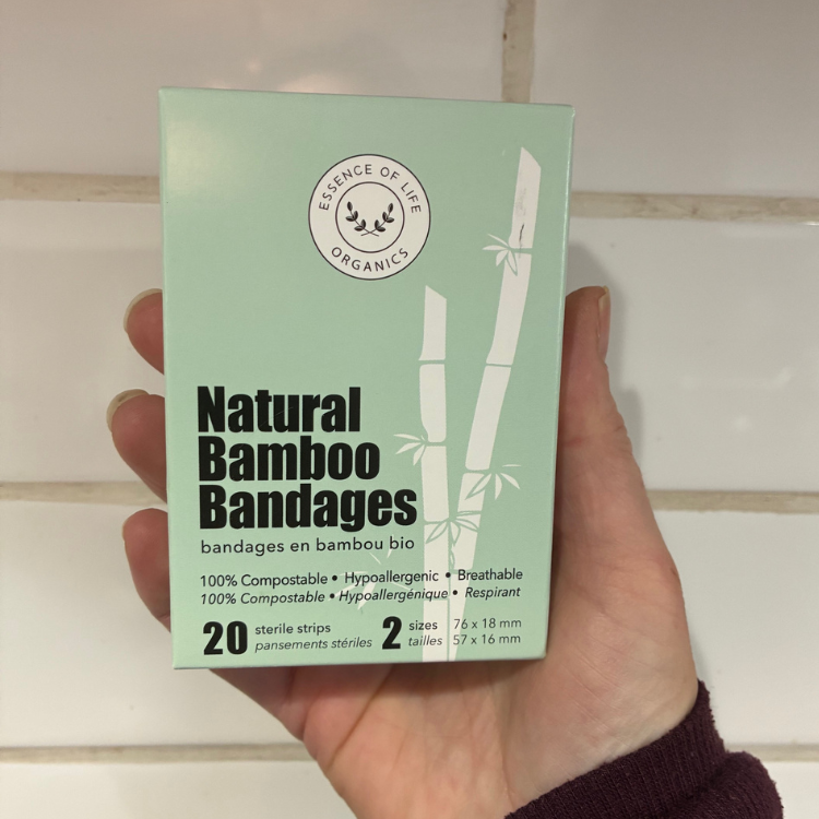 Une boite de bandages naturels et compostables de couleur verte claire tenue dans une main
