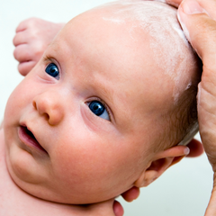 Un bébé se fait laver les cheveux avec une barre de shampoing adapté à lui. 