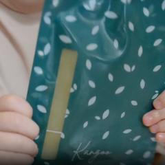 Pochette à boire réutilisable bleu-verte tenue dans des mains d'enfant. 