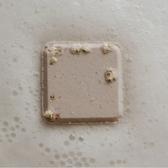 Un petit carré blanc parsemer de petites fleures blanche entourer de mousse de bain. 