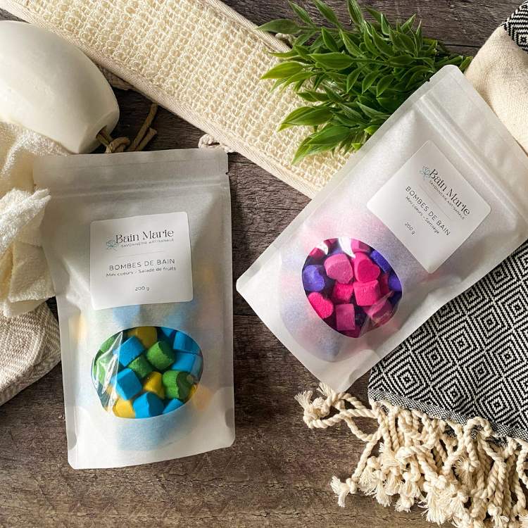 2 sacs de bombes de bain miniature naturelles déposés sur une planche de bois avec des articles de bains écologiques