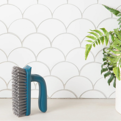 Brosse à plancher ou à récurer fabriquée en filet de pêche debout à côté d'une plante