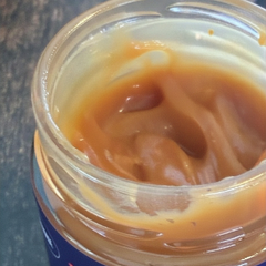 Pot de caramel fait au Québec ouvert démontrant un caramel onctueux déposé sur une planche de bois