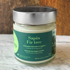 Chandelle naturelle et végane 35 heures sur un comptoir blanc avec un fond de bois fabriquée par Eco Loco de senteur Sapin 
