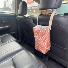 Corbeille poubelle de voiture accrochée sur un banc de cuir noir avec un motif bronze et tacheté
