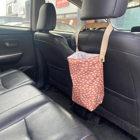 Corbeille poubelle de voiture accrochée sur un banc de cuir noir avec un motif bronze et tacheté