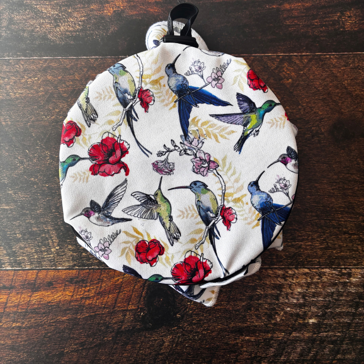 Couvre-plat au motif de colibris avec des fleurs sur un bol et une table de bois foncée