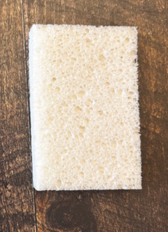 Éponge rectangulaire blanche sur un fond en bois foncé