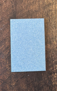 Éponge rectangulaire bleue sur un fond en bois foncé