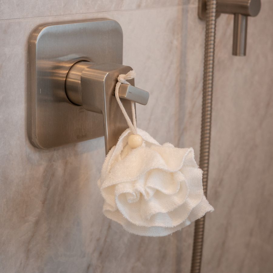 Houppette blanche accrochée sur la poignée de la douche