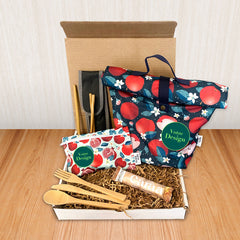 Une boîte cadeau écoresponsable avec à l'intérieur une boite à lunch, un sac à collation réutilisable, une barre de chocolat caramel caraa et des ustensiles en bois