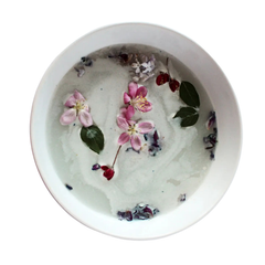 Un bol blanc avec un liquide laiteux et des fleurs sur un fond blanc. 